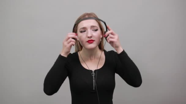 Młoda blondynka w kurtce wkurzona kobieta ze słuchawkami słuchającymi muzyki — Wideo stockowe