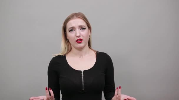 Jovem loira de casaco preto mulher confusa espalha as mãos — Vídeo de Stock