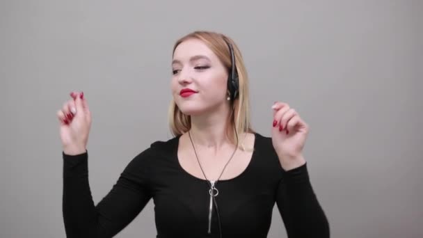 Meisje in zwart jasje vrouw luistert naar muziek in een oortje dansen, beweegt handen — Stockvideo