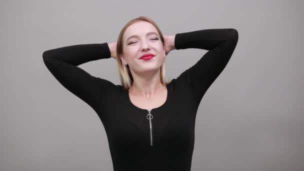 Joven chica rubia en chaqueta negra mujer feliz sostiene sus manos detrás de la cabeza — Vídeos de Stock