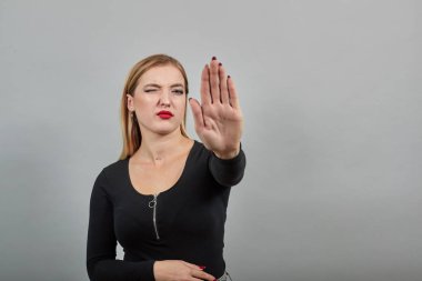 blonde girl in black jacket angry woman stops with hand gesture, shows palm