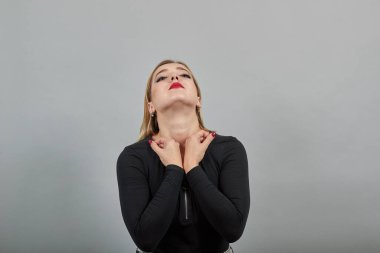 Young blonde girl in black jacket upset woman holds fists at throat