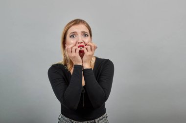girl in jacket upset woman in despair holds hands near mouth, frightened eyes