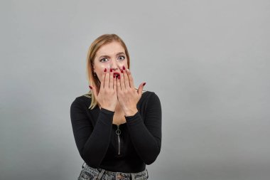 blonde girl in black jacket upset woman shows off manicure, shows fingernails