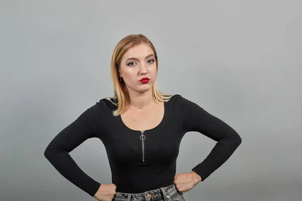 Serious woman confidently looks at the camera, keeps her hands on waist — Stockfoto