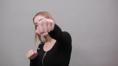 Young blonde girl in black jacket woman Boxing, punches