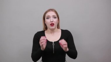Young blonde girl in black jacket terrified woman holds her hands to face