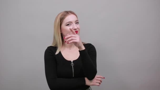 Girl in black jacket on grey background smart woman thinks, holds hand to face — Stockvideo