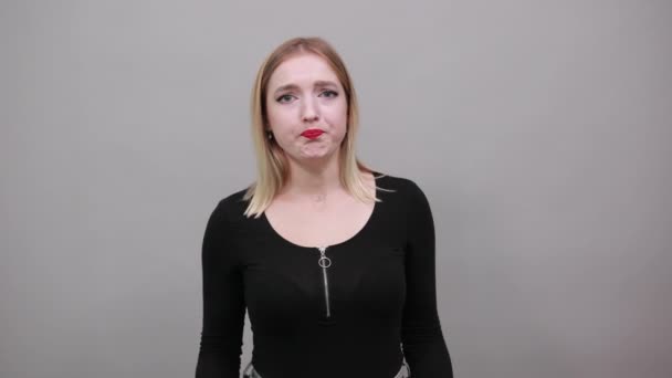 Young blonde girl in black jacket dreamy woman doubts, spreads her arms wide — Stock video