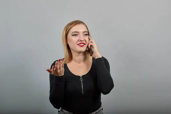 Happy woman talking on the phone, holding smartphone in hand and smiling — Stockfoto