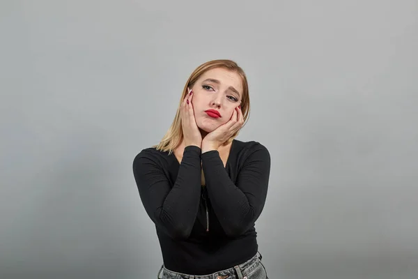 Young blonde girl in black jacket sad woman in depression, leans head on hands — Zdjęcie stockowe