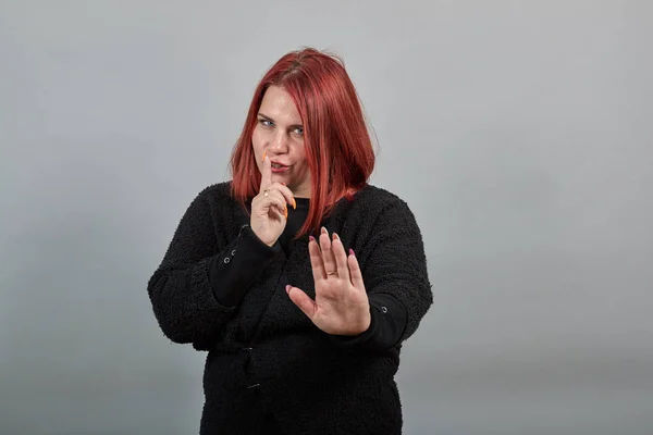 Fat girl in black sweater secret woman wants silence, holds index finger mouth — Stockfoto