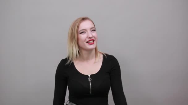 Young blonde girl in black jacket happy woman holds up her hand — Stockvideo