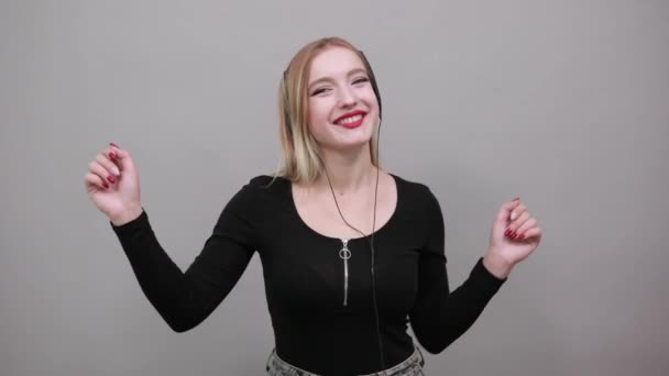 Дівчина в чорній куртці щаслива жінка слухає музику з навушниками та танцями — стокове відео