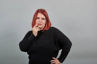 redhead fat lady in black sweater seductive woman touches index finger to lip