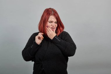lady in black sweater suffering woman holds her chin with hand grimaces in pain