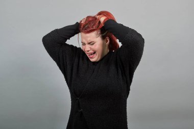redhead fat lady in black sweater annoyed, upset woman holding hair in despair