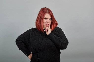 fat lady in black sweater stylish woman poses for camera, holding chin with hand