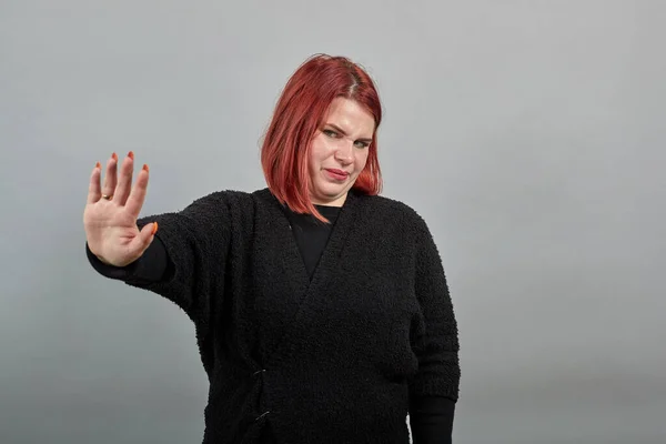 fat lady in black sweater angry woman shows hand stop gesture, doesnt agree