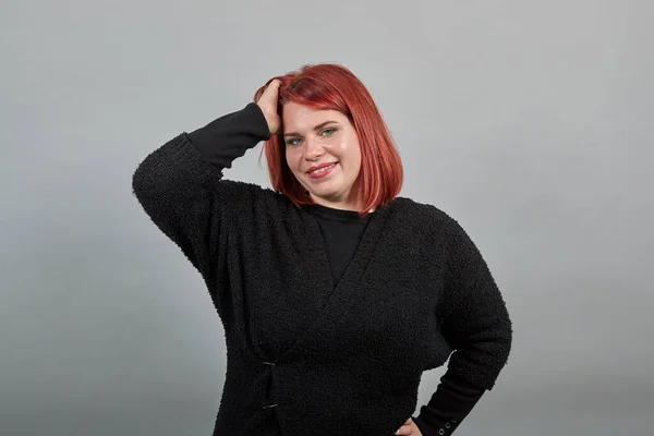 fat lady in black sweater happy woman smiles and touches head, hair with hands