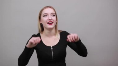 Young blonde girl in black jacket funny woman grimaces, makes different faces