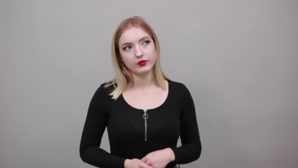 Serious woman confidently looks at the camera, keeps her hands on waist — Stockvideo