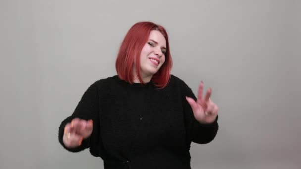 Young redhead fat lady in black sweater happy woman shows two fingers on hands — Wideo stockowe