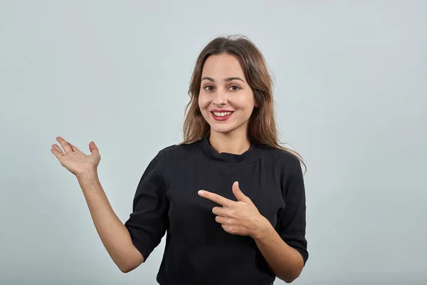 Sorrindo menina feliz mostra seus dedos na direção do lado — Fotografia de Stock