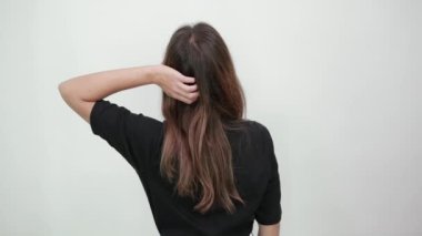 Esmer kadın kameraya döndü ve elini uzun saçlarıyla tuttu.