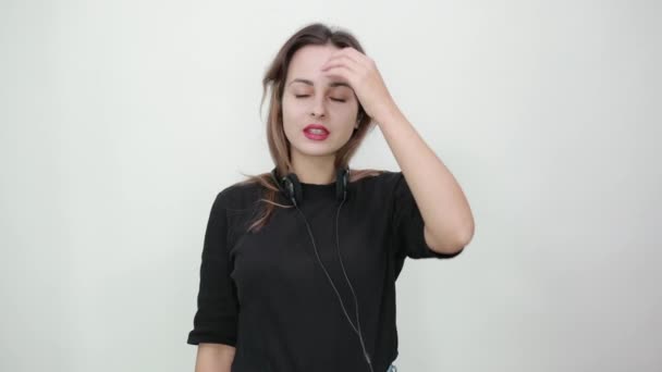 Chica desconcertada con auriculares en el cuello se sorprende por la noticia — Vídeos de Stock