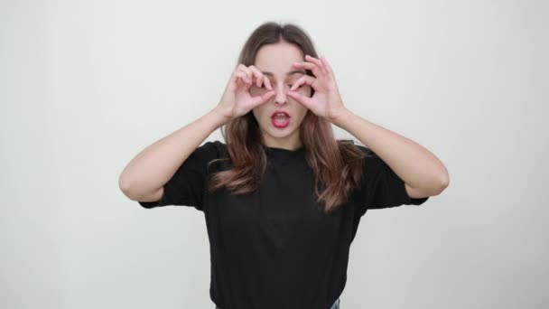 Chica sorprendida hizo un signo OK con los dedos delante del ojo y mira hacia adelante — Vídeos de Stock