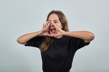 Duyguları olan sinirli bir kız çığlık atar, ellerini yüzüne tutar.