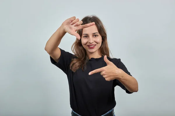 Menina feliz sorri demonstra com suas mãos imitação da câmera, tira foto — Fotografia de Stock