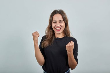 Gülümseyen mutlu kız ellerini yumruk yapıp ellerini kaldırdı.