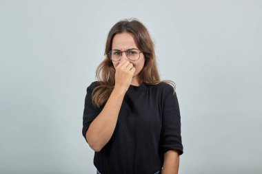 Kötü bir kokudan dolayı yüzünü buruşturan, burnunu eliyle kapatan bir kadın.