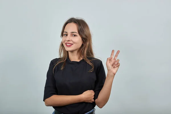 Menina feliz sorri e mostra seus dedos um sinal de paz ou vitória — Fotografia de Stock