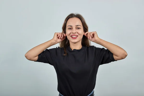 Ragazza felice sorride e tocca i lobi delle orecchie con le mani — Foto Stock