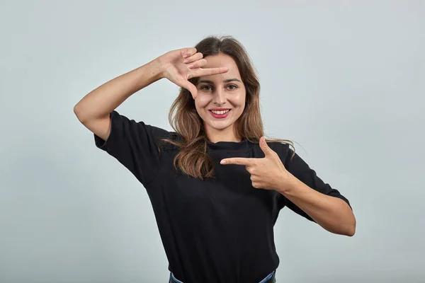 Glückliches Mädchen lächelt und macht eine Imitation des Rahmens mit ihren Fingern — Stockfoto