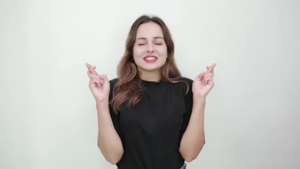 Boldog lány mosolyog a szerencséért, szorítja az ujjait — Stock videók