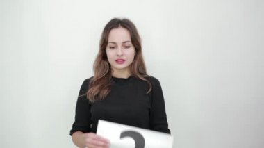 Kız ne yapacağını bilemiyor. Üzerinde soru işareti olan beyaz kağıt tutuyordu.