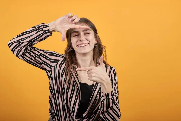Glad flicka ler med sina fingrar gör en virtuell ram som foto — Stockfoto