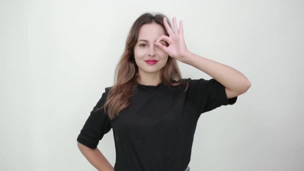 Happy Girl Smiles And Holds Her Fingers Up To Her Eyes, Bent In The Ok Sign — Stock Video