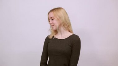 Mutlu kız gülümser, ellerini göğsüne sokar ve başka yere bakar..