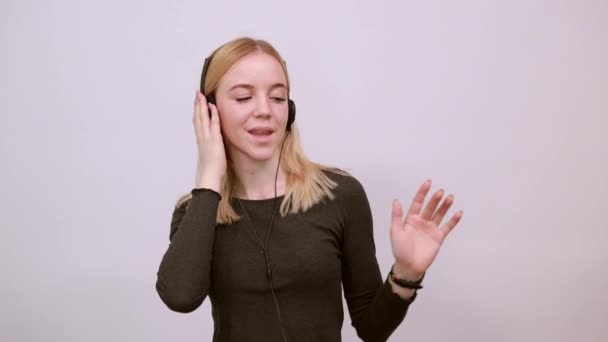 Boldog vonzó lány mosolyog, becsukja a szemét, és zenét hallgat fejhallgatón — Stock videók