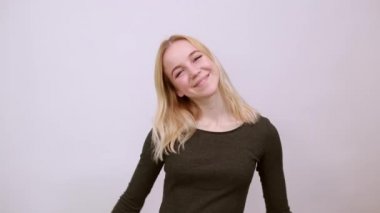 Mutlu kız gülümsüyor, ellerini birbirine yapıştırıyor ve yüzünü buruşturuyor..