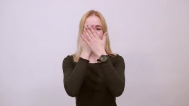 Mutlu kız gülümser ve elleriyle gözlerini kapatır. Utangaçlık kavramı