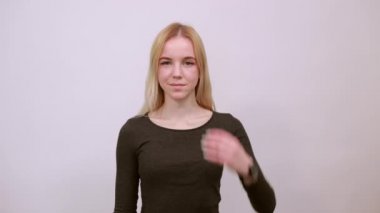 Aptal kız eğleniyor, elleriyle başını tutuyor, dilini uzatıyor.