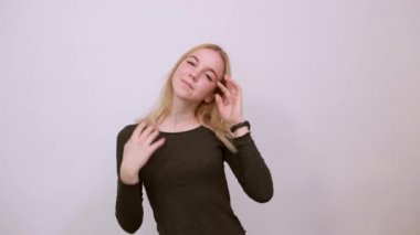 Aptal kız eğleniyor, iki parmağını gözünün içine sokuyor, dilini dışarı çıkarıyor.