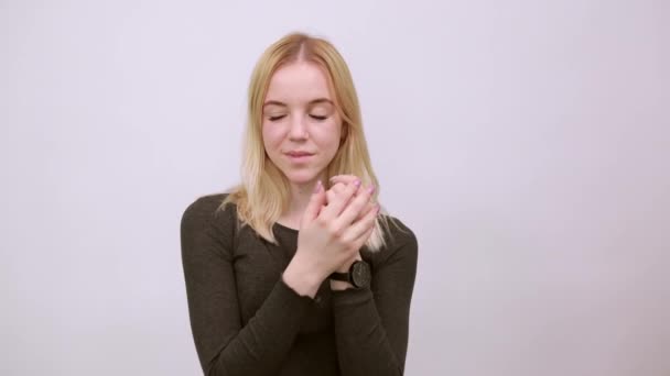 Ragazza carina tiene insieme le mani vicino al viso, sembra amichevole con amore — Video Stock