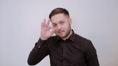 Mutlu Erkek Gülüşü, parmaklarıyla imzalar, gözlerine tutar. Tamam..